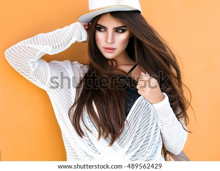 Amazing teen girl posing at that street at autumn -spring outfit,cap,denim jeans,sport bag,happy and positive girl,glam rock style,teen hipster trend outfit, positive mood, smiling, amazing model girl Royalty-Free Stock Photo #489562429