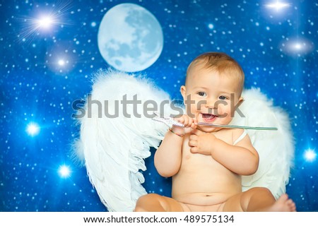 Baby a few months with magic wand and angel wings plays on us blue sky and stars