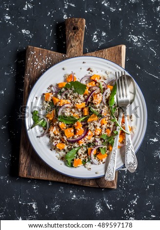 Salad with quinoa and roasted pumpkin. On a dark background, top view
