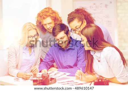 business, office and startup concept - smiling creative team with photocameras and images working in office