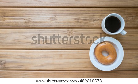 Dessert and drink image of donut or doughnut and hot coffee on vintage wooden table , top view background