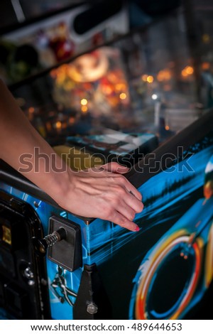 Hand of female pressing button and playing pinball machine Royalty-Free Stock Photo #489644653