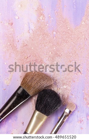 Makeup brushes on a light purple watercolor background, with traces of powder and blush on it. A vertical template for a makeup artist's business card or flyer design, with copyspace