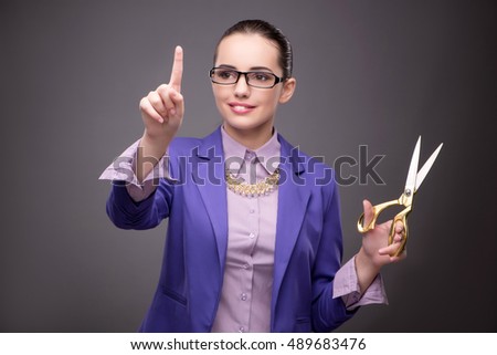 Young woman with scissors against gray background