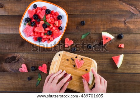 Plate with salad of watermelon, blackberries, mint. hand cut hearts of watermelon on a wooden board. On a wooden background.