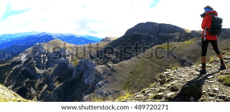 Climber taking a panoramic picture of an alpine landscape from the summit of a rocky peak, Pyrenees Mountains, Catalonia, Spain.