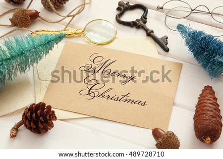 Top view of pine cones, greeting card, christmas tree and vintage objects on white wooden background