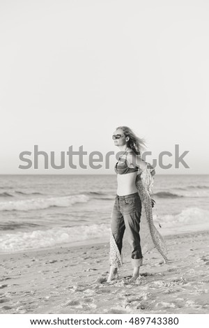 Black and white image of joyful woman walking on the beach at sunset nature outdoors background