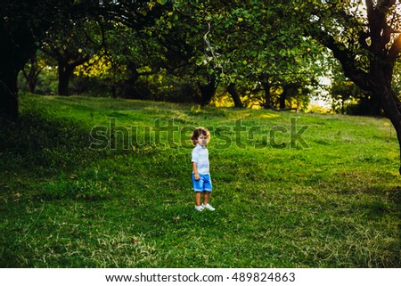 Cute little boy walking in a green park alone