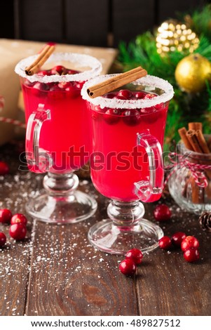 Festive Cranberry drink on Christmas background with fir branches and fresh berries, selective focus. Holiday concept. Dark rustic wooden table, Winter time