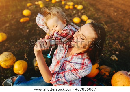 mother playing with her daughter on a field with pumpkins, Halloween eve