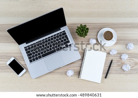 Modern working place on wooden table. Working place surrounded with notepad, coffee, pen, plant, wrinkled paper, iphon and macboo. Blank copy space view from above or top view. Dead ideas paper.
