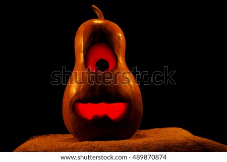 cheerful Halloween pumpkin minion isolated on black background with a glow inside