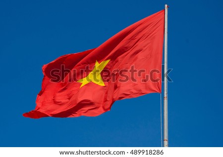 The flag of Vietnam (red flag with a gold star) fluttering on blue sky