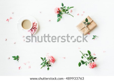 Workspace. Gift, cup of coffee and rose flowers. Flat lay, top view, copy space