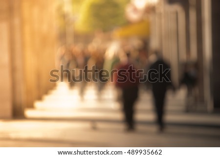 People walking down the street in the evening, beautiful light at sunset. The photo is purposely made out of focus, no faces are recognisible
