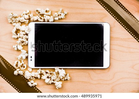 Tablet pc on wood with attributes of cinema. Visual metaphor for internet content - films and media on a mobile device.