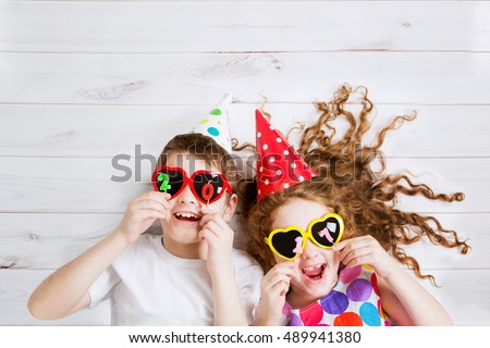 New Years 2017, christmas holiday. Funny children with sunglasses heart shape, hold 2017 candles, lies on the wooden floor. High top view. Royalty-Free Stock Photo #489941380