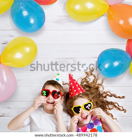 New Years 2017, christmas holiday. Funny children with sunglasses, hold 2017 candles, lies on the wooden floor. High top view. Royalty-Free Stock Photo #489942178