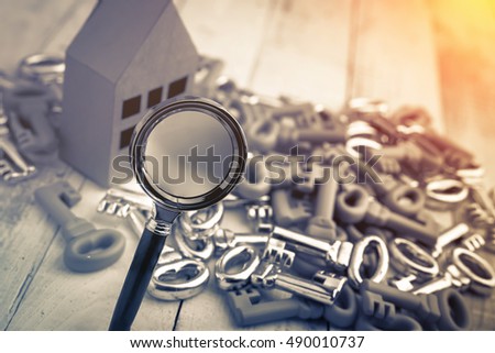 house model with silver keys and hand with magnyfying glass,business real estate concept