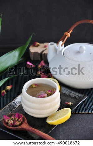 Rose tea cup on tray with tea pot on black background