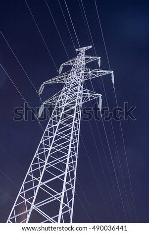 Large electricity pylon by night with dark starry sky as a background.