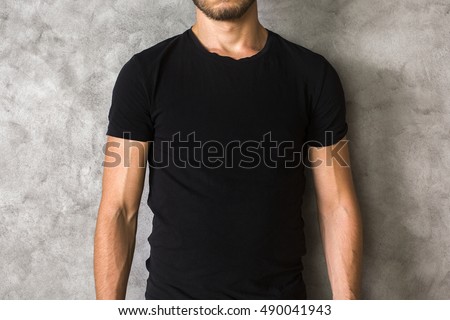 Closeup of young man's body in empty black t-shirt on textured concrete wall background. Mock up Royalty-Free Stock Photo #490041943