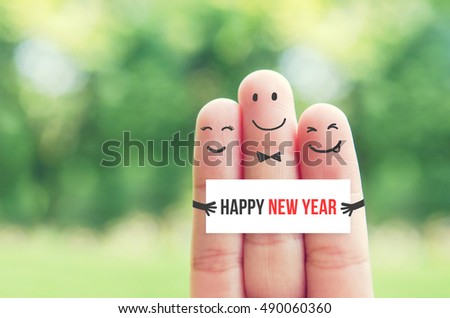 New Year concept, Happy finger art family group holding blank paper with Happy New Year message while smiley face at blurred outdoor park background.