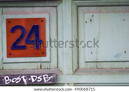 Blue number 24 on a red background hang on a green wooden doors