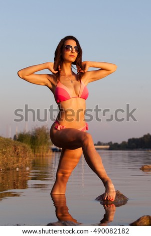 Sportive bikini girl standing in a river at evening