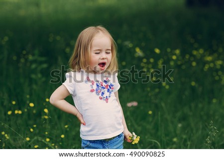 beautiful little girl in the meadow near tree posing and smiling