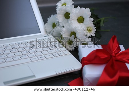 laptop, bouquet of daisies and gift