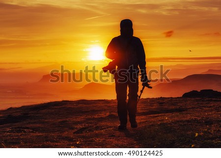 Happy man standing on a cliff at sunset.