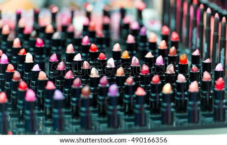 Beautiful big multicolor professional makeup set of many different colorful lipsticks in black plastic tubes in show case, horizontal picture