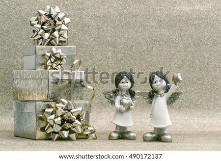 Gift box with ribbon and little angels on shiny background. Holidays decoration. Vintage style toned picture