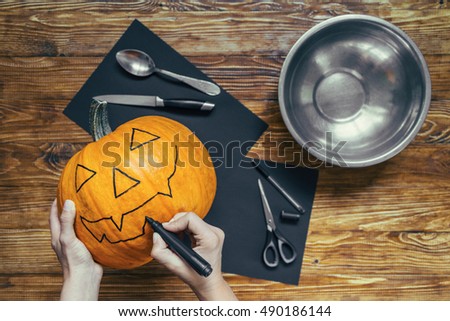 Carved Halloween pumpkin smiling in the night next to leaves. Pumpkin on the wooden deck. Scary and happy halloween greeting card and background. making pumpkin head