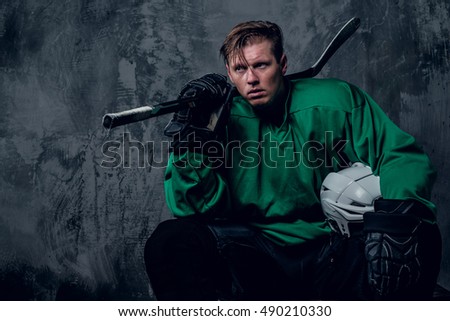 Tired hockey player relaxing on grey background.