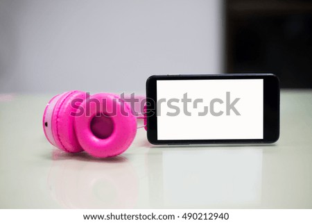 pink headphones and smart phone on table in office