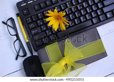 black computer keyboard, gift with yellow ribbon and office supplies on a white background