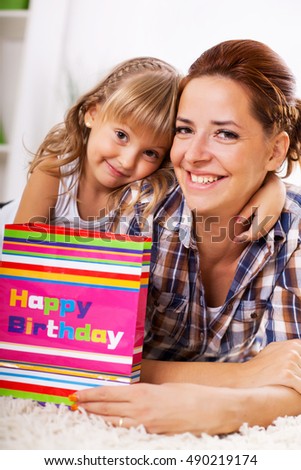 Happy mother and daughter with birthday present. smiling and looking at camera. 
