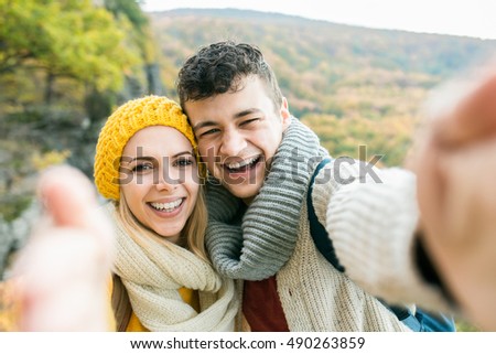 Young couple on a walk in autumn forest taking selfie