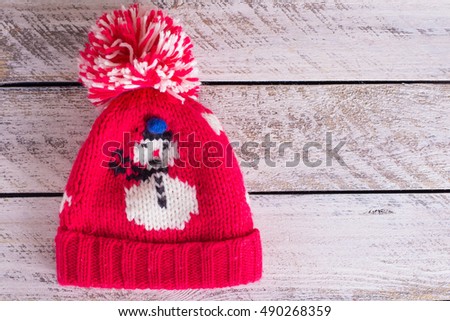 Christmas Red knitted hat with snowman, wooden background, copy space