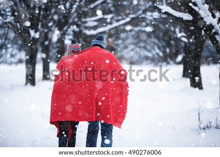 A loving couple walking in winter park. The snowfall
