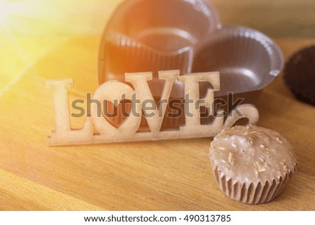 Love and chocolate on wood table and rays light from the window