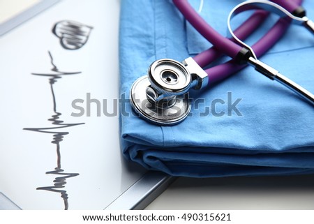 Doctor coat with medical stethoscope on the desk .