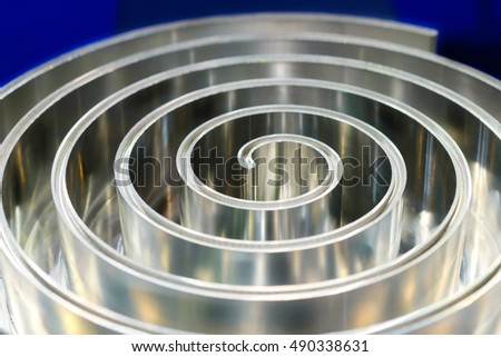 Metal spiral of polished aluminum. Abstract background. Toning in the color blue industrial cold metal. Shallow depth of field.