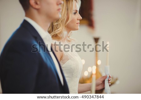 bride and groom hold candles at the wedding ceremony in church