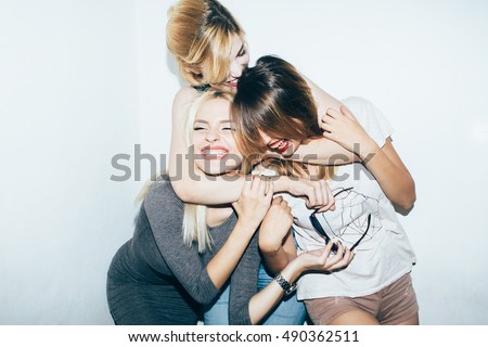 Three female friends posing in front of white wall