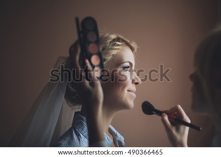 make-up artist doing professional make up of young woman.