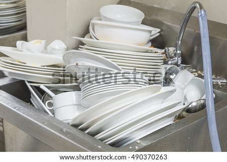 The plate dishes in the kitchen waiting for cleaners in sink